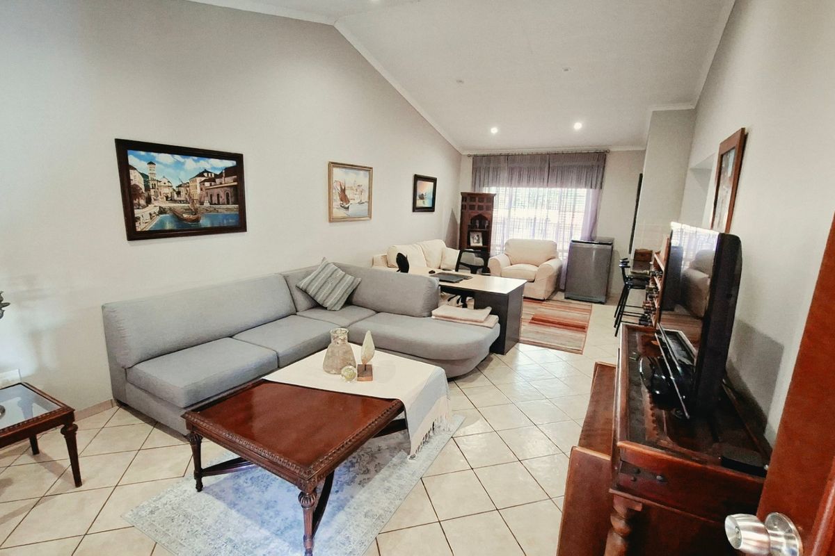 Spacious living room featuring vaulted ceilings, tiled flooring, and recessed lighting, offering a comfortable and open atmosphere.