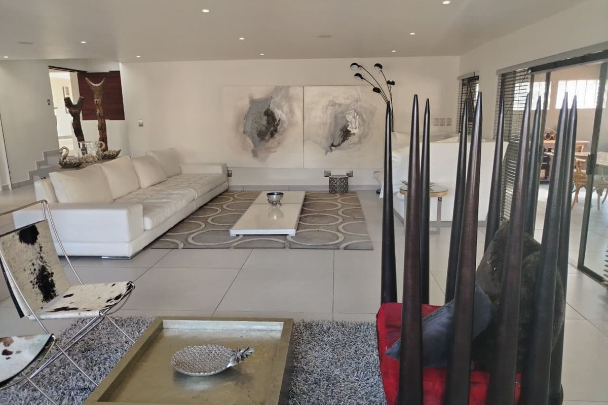 Spacious, modern living area featuring large format floor tiles, recessed downlighting, and expansive sliding glass doors leading to the exterior.