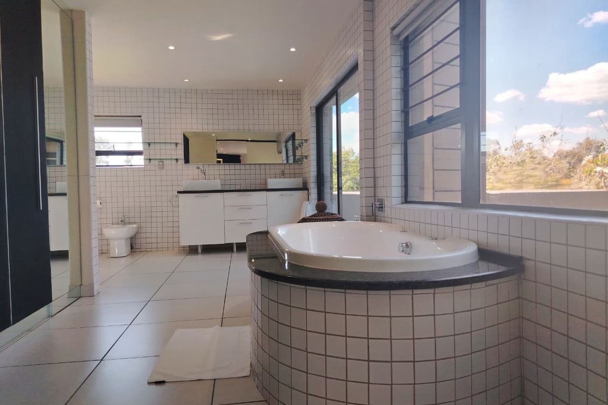 Spacious modern bathroom featuring a built-in bathtub, dual vanity with vessel sinks, bidet, and large windows providing ample natural light.