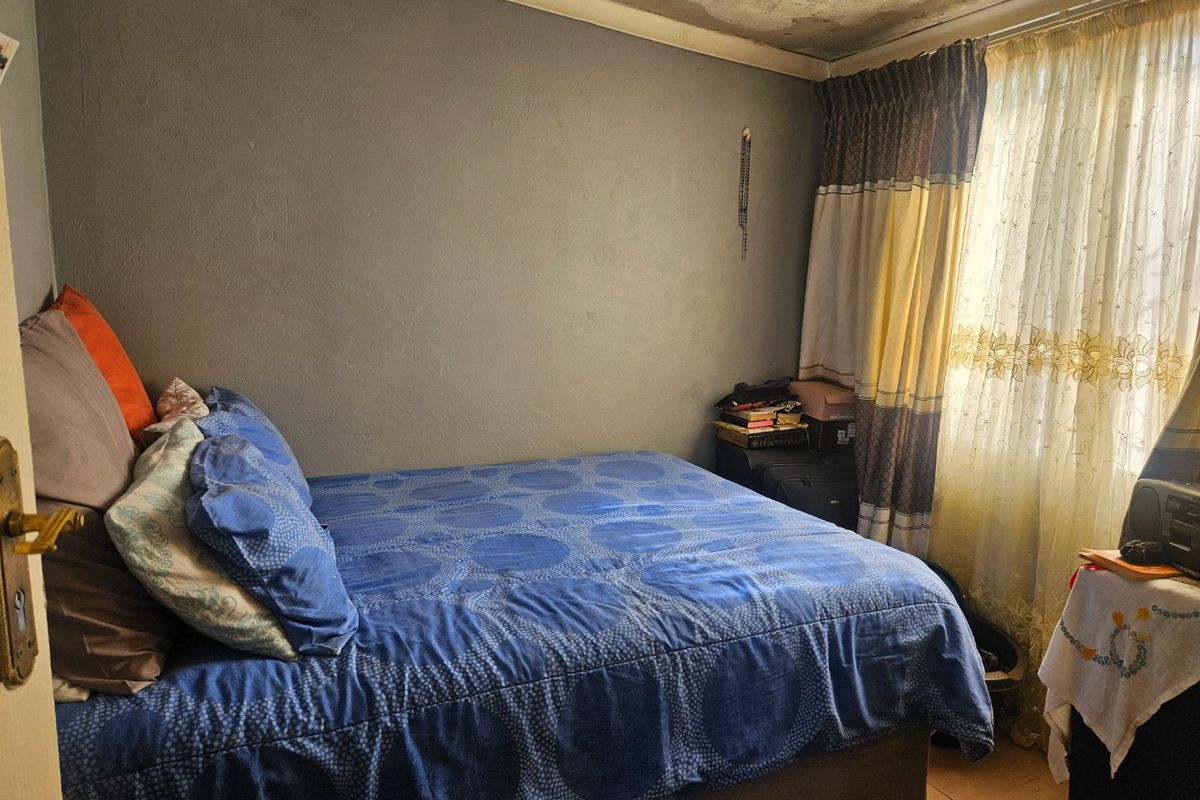 A bedroom featuring tiled flooring and curtain rails, currently showing significant signs of ceiling water damage requiring repair.
