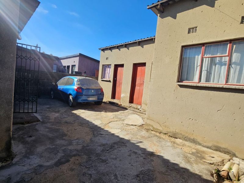 Rear exterior view of the property featuring a concrete paved courtyard area and plastered building facades.