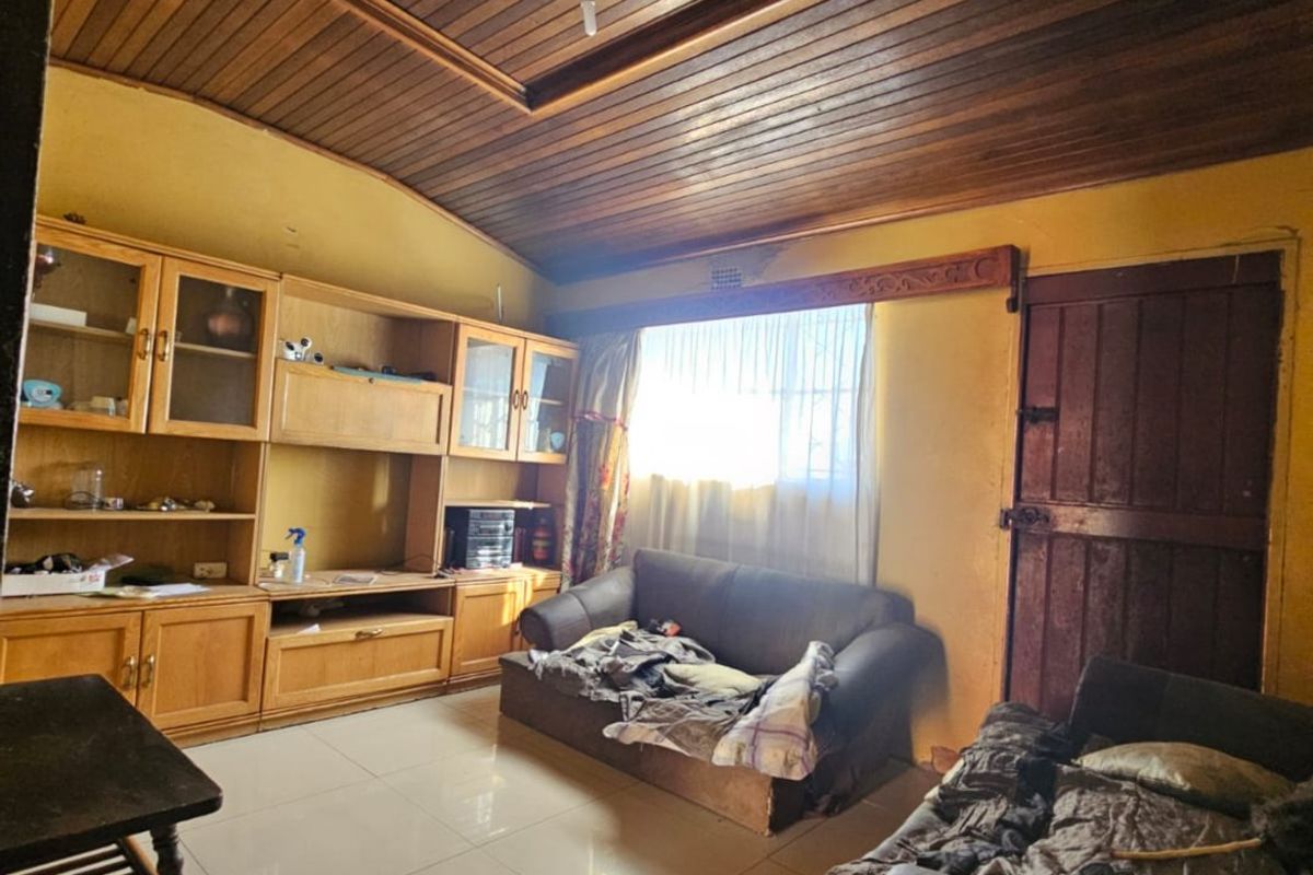 Living room featuring a timber-clad ceiling, tiled flooring, and built-in cabinetry, offering a dated aesthetic with potential for modernization.