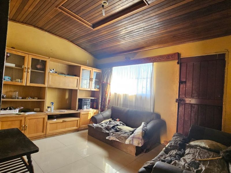 Living room featuring a timber-clad ceiling, tiled flooring, and built-in cabinetry, offering a dated aesthetic with potential for modernization.