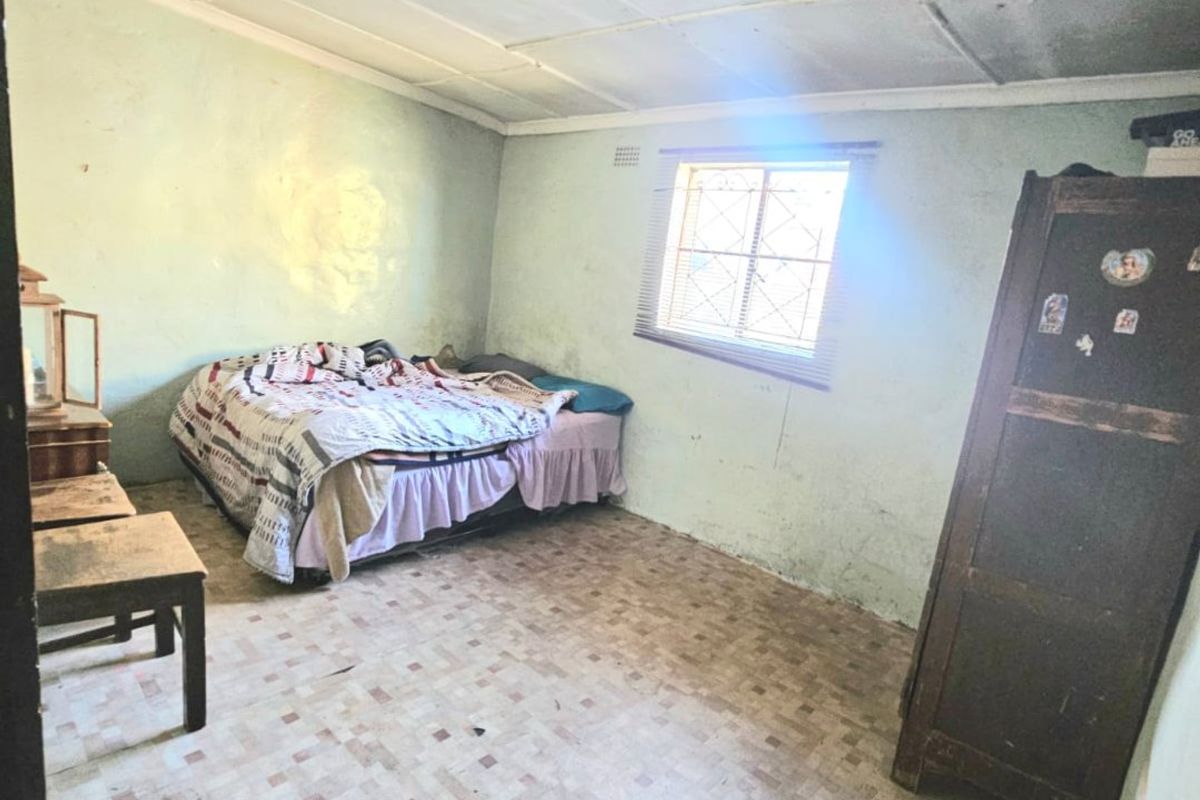 A bedroom featuring tiled flooring and a tiled ceiling, currently showing significant signs of wear and requiring cosmetic refurbishment.