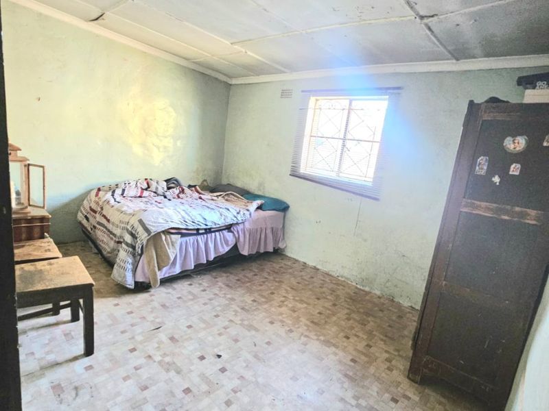 A bedroom featuring tiled flooring and a tiled ceiling, currently showing significant signs of wear and requiring cosmetic refurbishment.