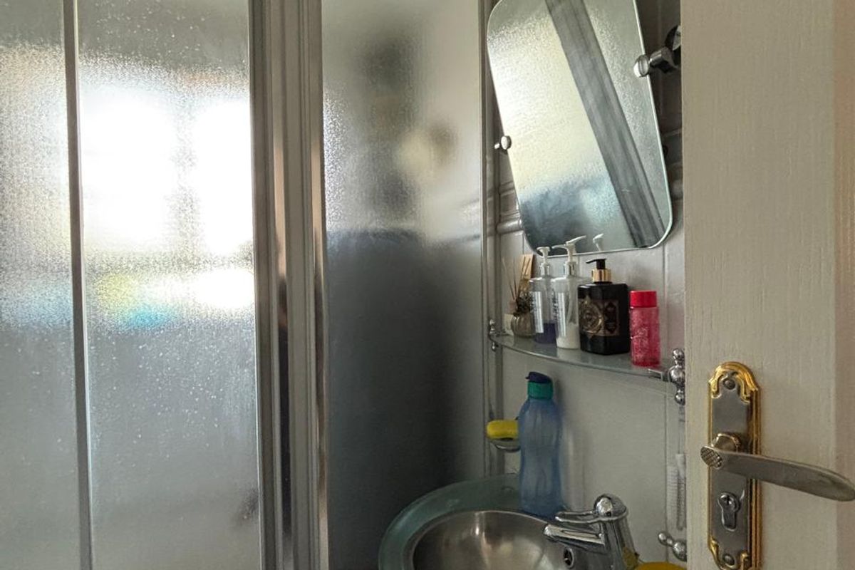 Compact bathroom featuring a glass pedestal sink, chrome fixtures, and a sliding glass shower enclosure with tiled wall finishes.