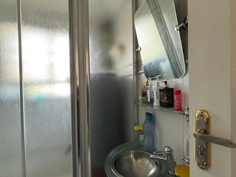 Compact bathroom featuring a glass pedestal sink, chrome fixtures, and a sliding glass shower enclosure with tiled wall finishes.