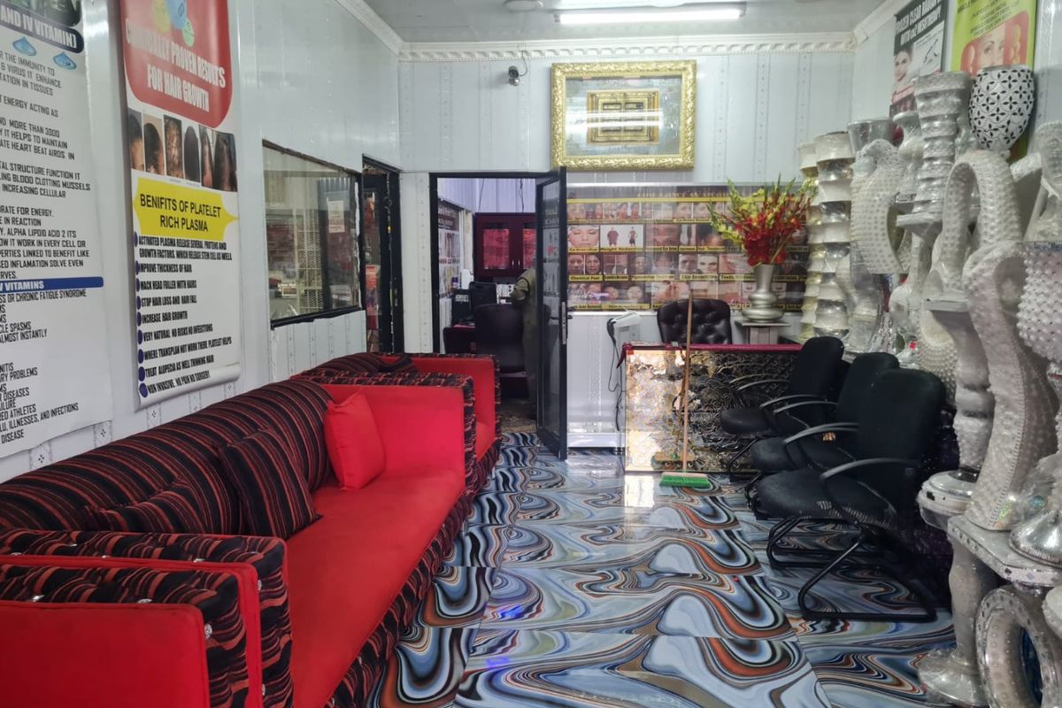 Interior view of a commercial space featuring patterned tiled flooring and decorative wall molding, currently utilized as a clinic or salon.