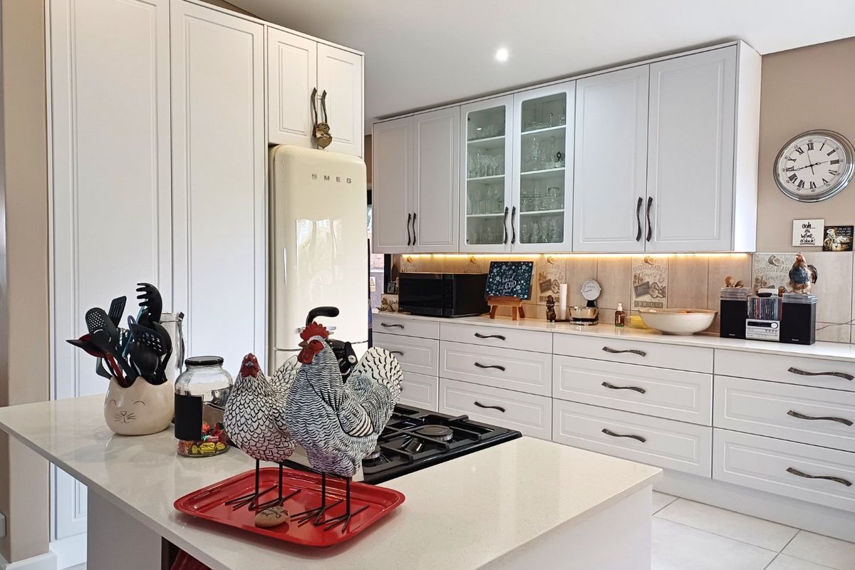 Modern kitchen featuring white shaker-style cabinetry, quartz countertops, a central island with a gas cooktop, and elegant under-cabinet lighting.