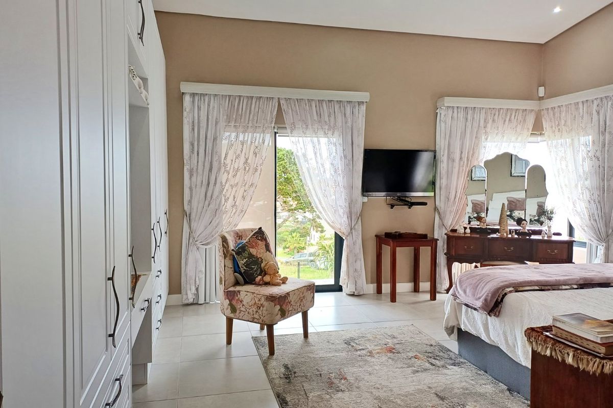Spacious bedroom featuring neutral walls, tiled flooring, extensive built-in cabinetry, and sliding glass doors providing natural light and garden access.