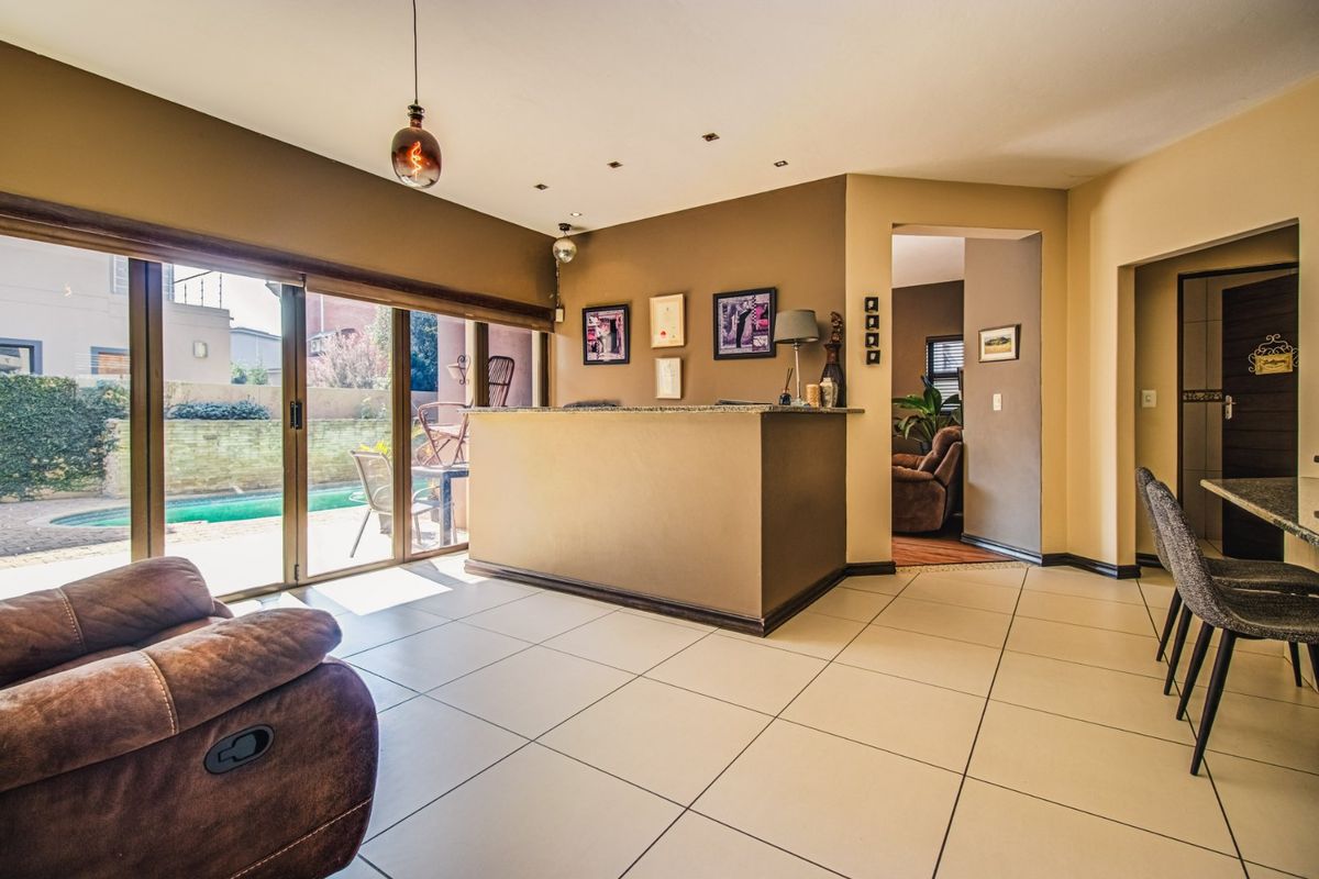Living area featuring a built-in bar counter, tiled flooring, and large sliding glass doors providing direct access to the outdoor pool area.