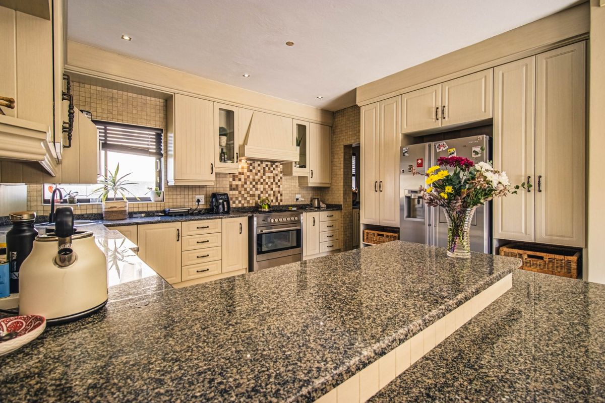A well-appointed kitchen featuring granite countertops, extensive built-in cabinetry, a stainless steel oven, and a decorative mosaic tile backsplash.
