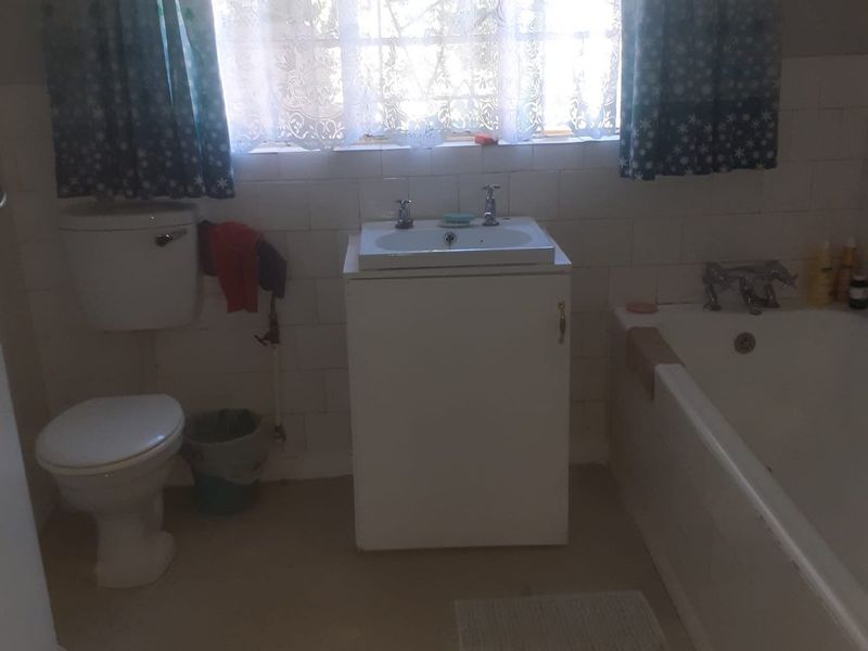 A functional bathroom featuring a standard bathtub, vanity basin, and toilet with tiled wall finishes.