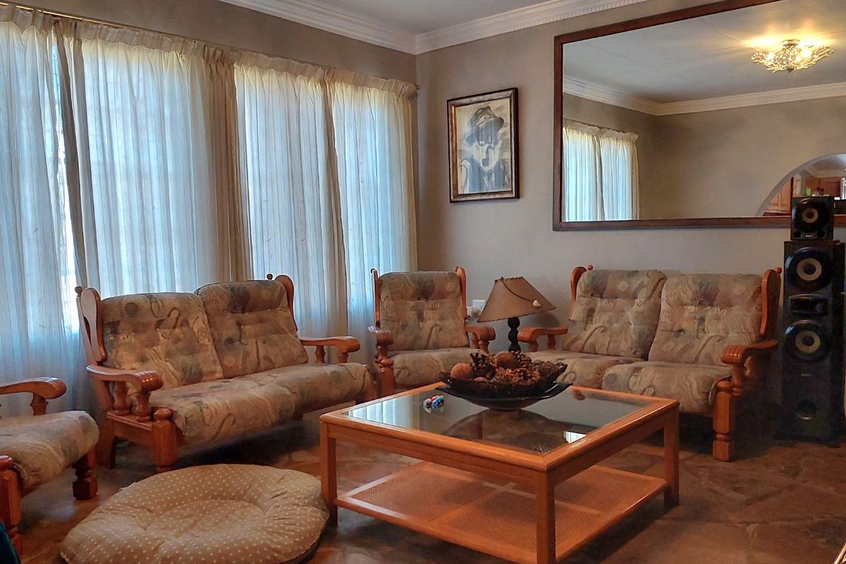 A comfortable living room featuring stone tile flooring, crown molding, and a large wall-mounted mirror, providing a classic and inviting atmosphere.