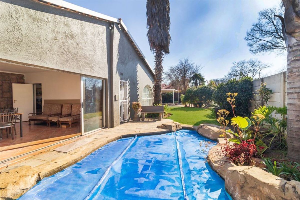 Outdoor pool area featuring a swimming pool with cover, rock landscaping, and direct access to the interior living space via sliding glass doors.