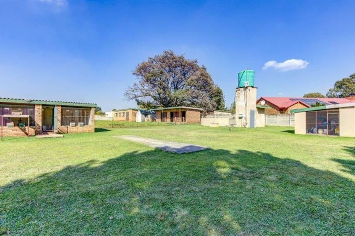 Spacious rear yard featuring multiple brick outbuildings, a water tank tower, and a concrete slab area on a large farm property.