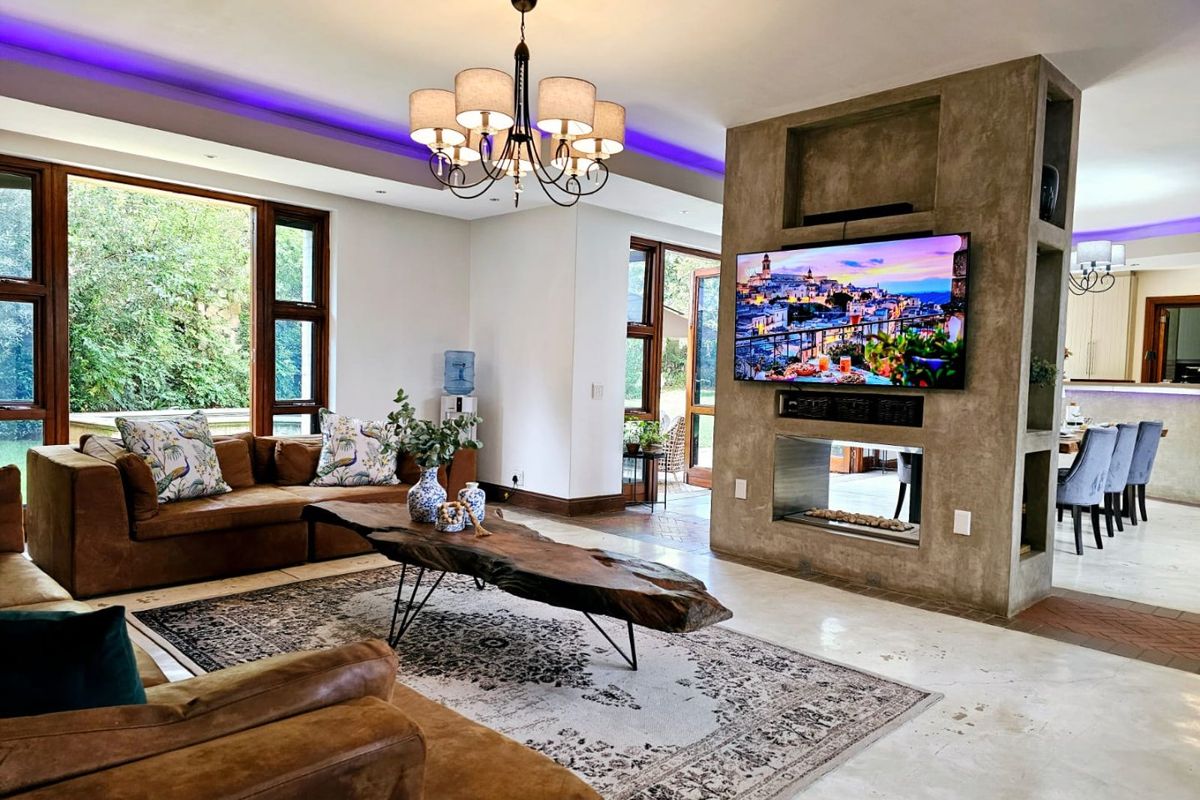 Spacious living room featuring polished concrete floors, a central built-in fireplace with integrated shelving, and elegant cove lighting.