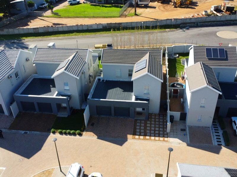 Aerial view of a modern residential complex featuring multiple houses with tiled roofs, solar panels, and paved driveways.