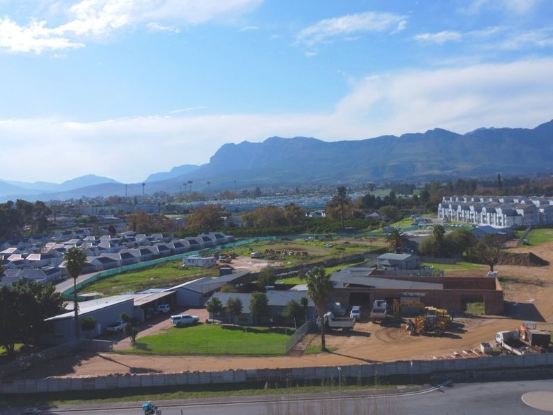 An aerial view of the property site showing surrounding residential development, mountain vistas, and ongoing construction activity on the grounds.