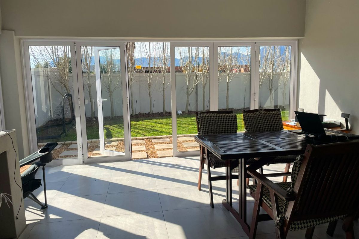 Bright living area featuring large format floor tiles and expansive folding glass doors that open directly onto a private garden.