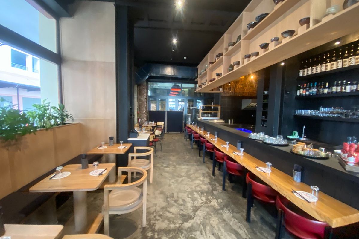 Modern commercial restaurant space featuring a long built-in bar, polished concrete floors, and large windows providing ample natural light.