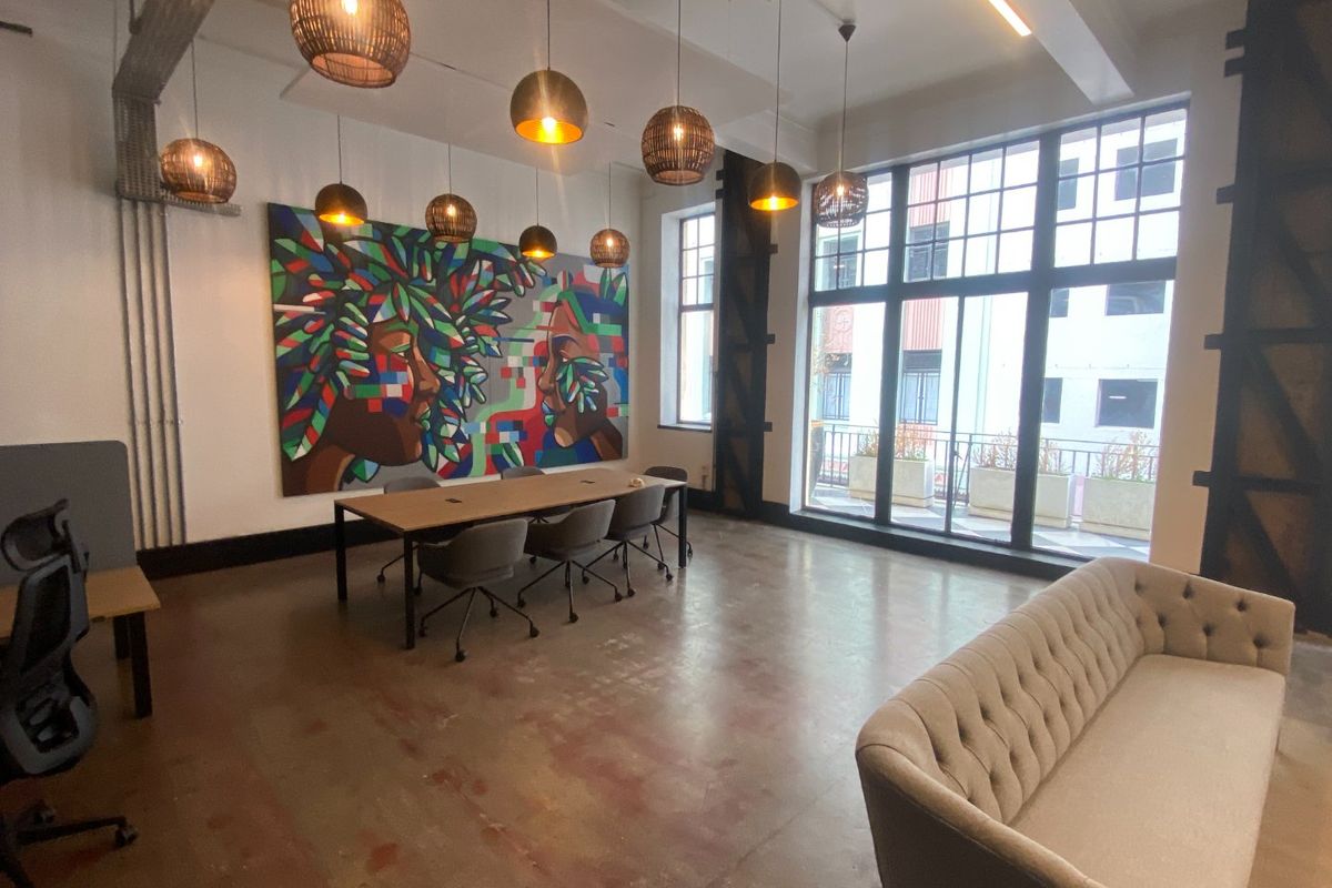 Modern industrial-style office space featuring polished concrete floors, large windows, exposed structural elements, and contemporary pendant lighting.