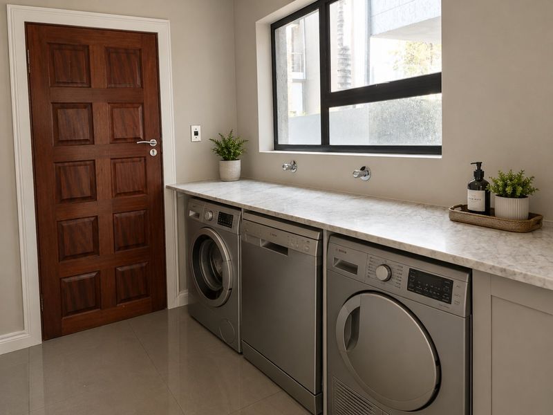 A modern, well-maintained laundry room featuring a marble countertop, tiled flooring, and integrated appliance connections.