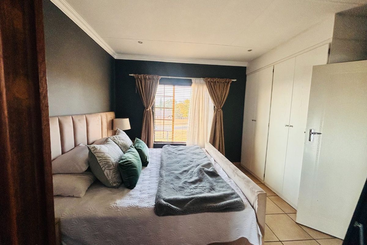 A well-maintained bedroom featuring built-in cupboards, tiled flooring, and recessed downlighting, offering a comfortable and functional living space.