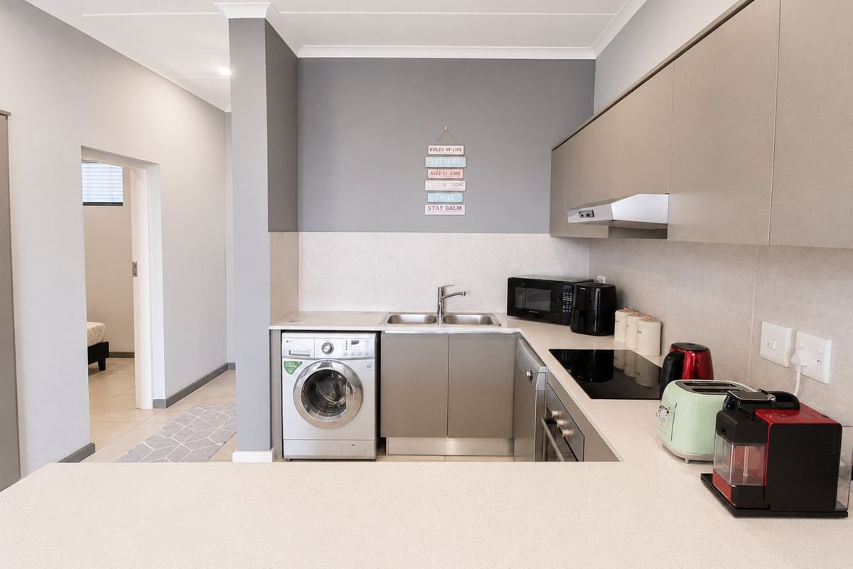 Modern kitchen featuring sleek cabinetry, stone countertops, integrated appliances, and a functional layout with a double sink and electric hob.