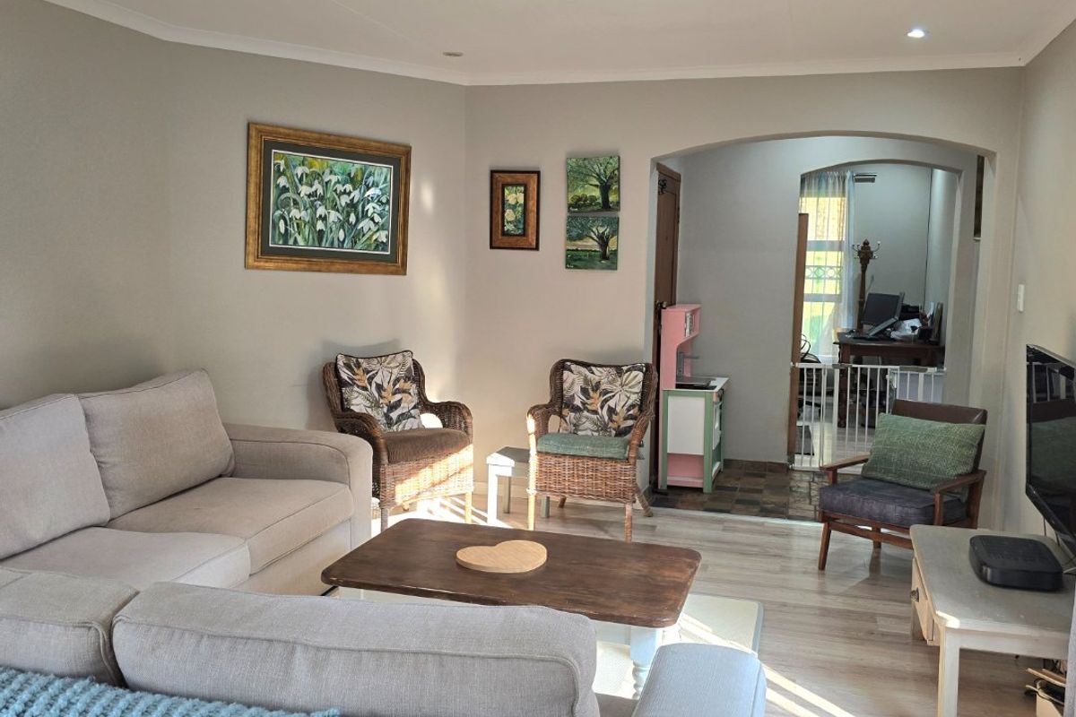 A comfortable living room featuring neutral walls, recessed downlighting, and laminate flooring, with an open archway leading to an adjacent space.