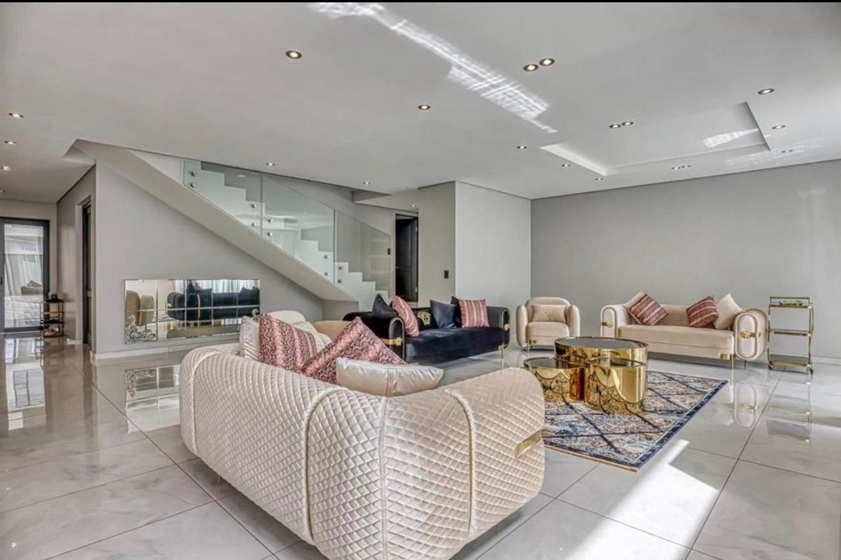 Spacious modern living room featuring high-gloss porcelain flooring, a contemporary glass balustrade staircase, and elegant recessed ceiling lighting.