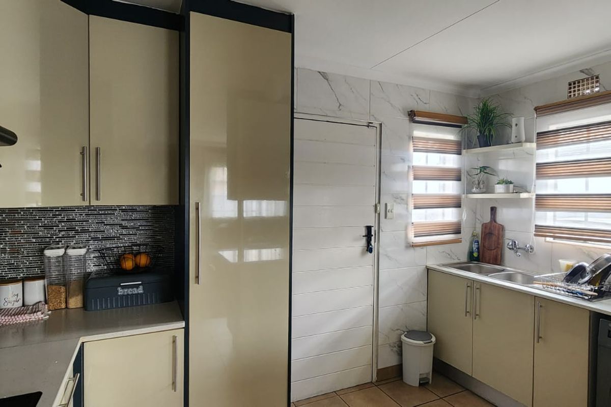 A functional kitchen featuring modern cabinetry, tiled splashbacks, double sink, and integrated plumbing for appliances, offering a clean and practical workspace.