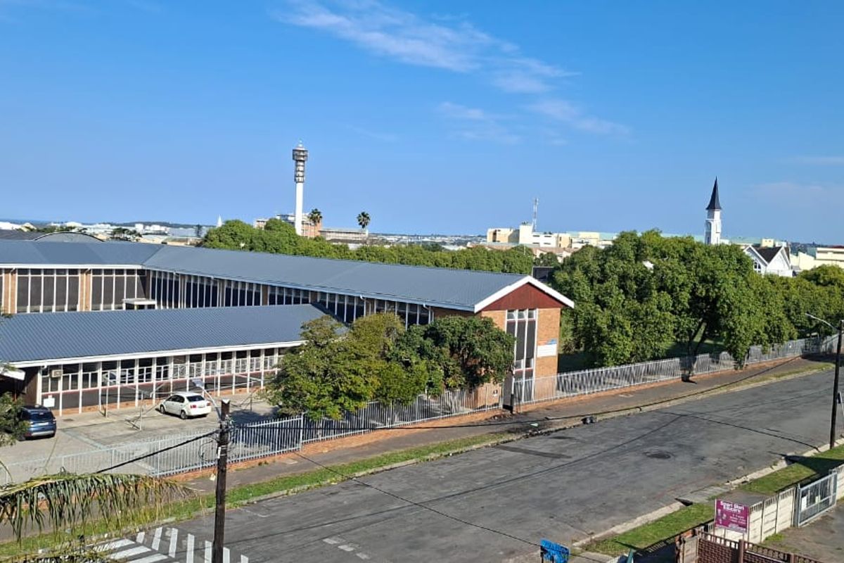 An elevated aerial view showing the surrounding neighbourhood, street access, and the exterior of the adjacent building complex.