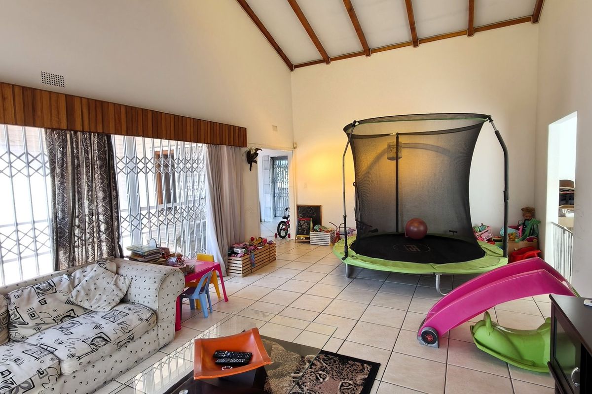Spacious living area featuring high vaulted ceilings with exposed timber beams and ceramic tiled flooring, offering a bright and open layout.