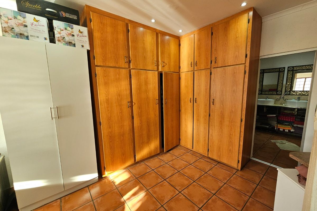 Bedroom featuring extensive built-in wooden cabinetry for storage and durable tiled flooring, with an adjacent view into a bathroom area.