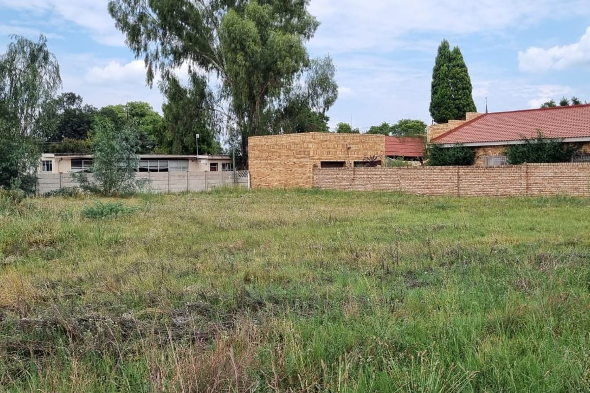 A vacant residential plot featuring established boundary walls and surrounding residential properties, offering a blank canvas for development.