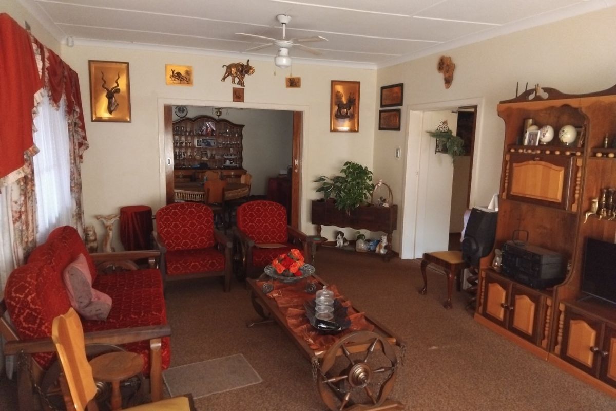 A traditional living room featuring a ceiling fan and carpeted flooring, with an open doorway leading to an adjacent dining area.