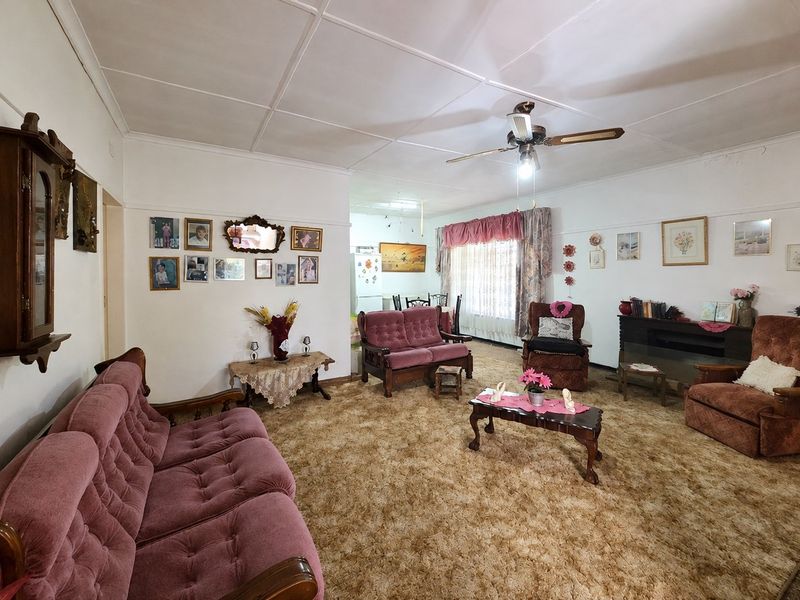 Spacious open-plan living area featuring a ceiling fan and carpeted flooring, offering a traditional layout with potential for modern updates.