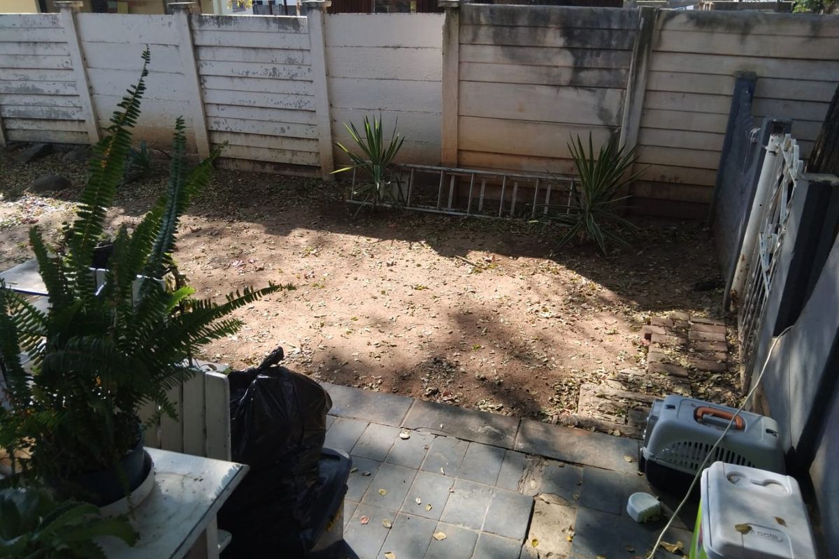 A rear courtyard area featuring a tiled patio and a precast concrete boundary wall in need of maintenance and landscaping.