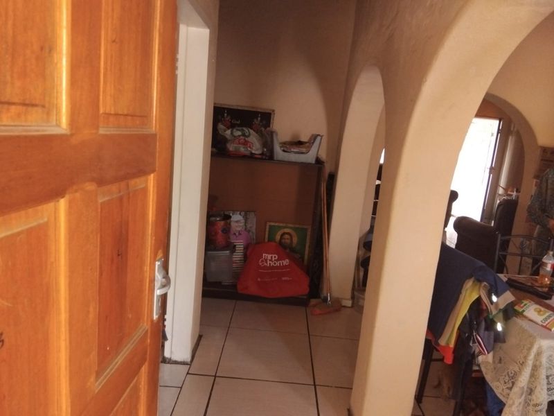 A hallway featuring arched architectural details and tiled flooring, providing access to adjacent living spaces.