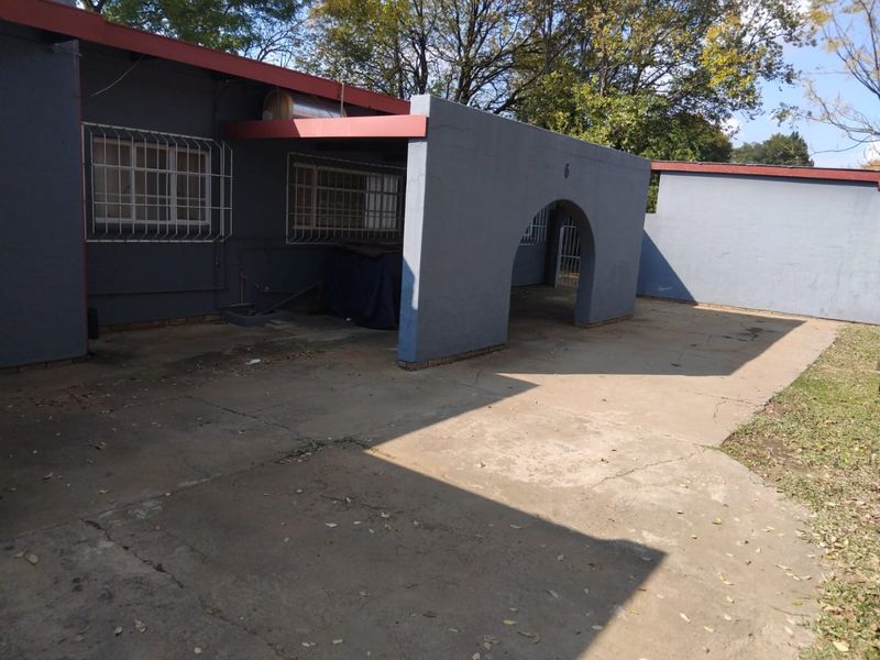 Front exterior view of the townhouse featuring a concrete driveway, arched entrance, and security bars on the windows.