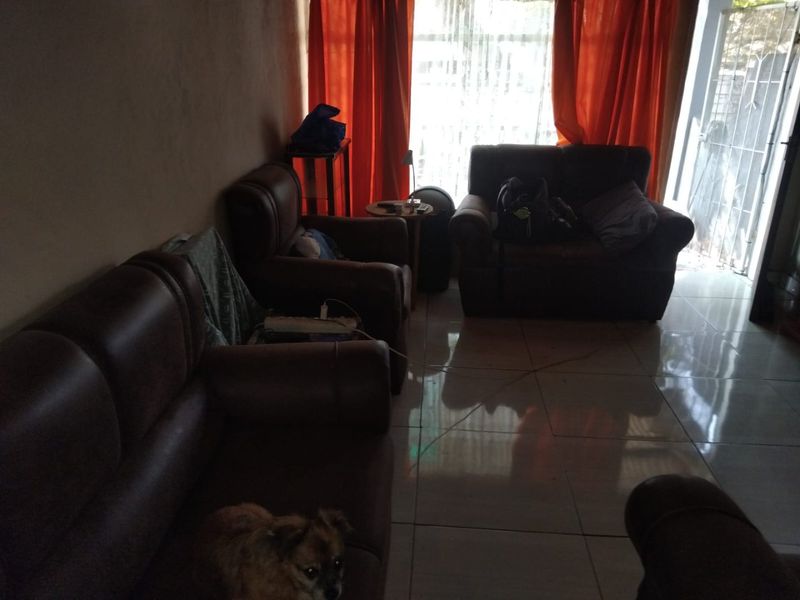 A living room area featuring tiled flooring and access to an exterior security gate, providing a functional space for relaxation.