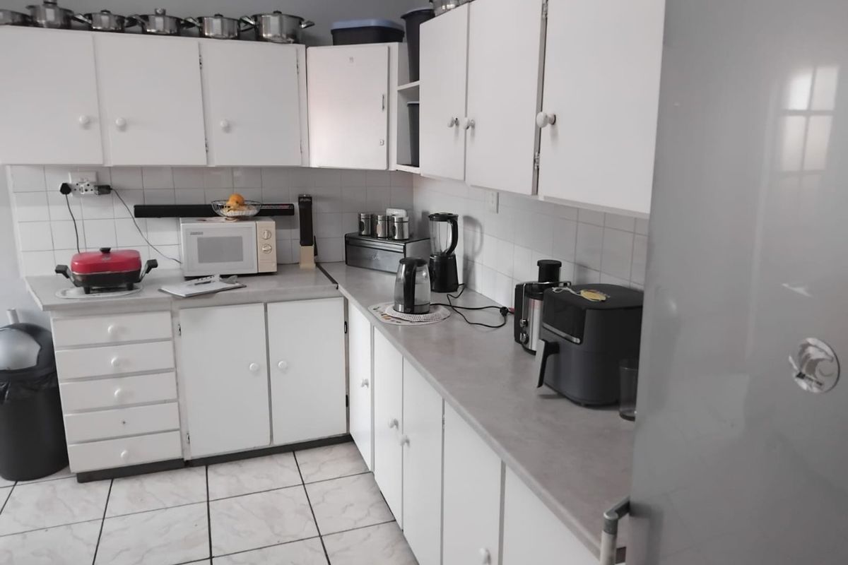 A functional kitchen featuring white cabinetry, laminate countertops, tiled backsplash, and tiled flooring, providing a practical workspace for daily meal preparation.