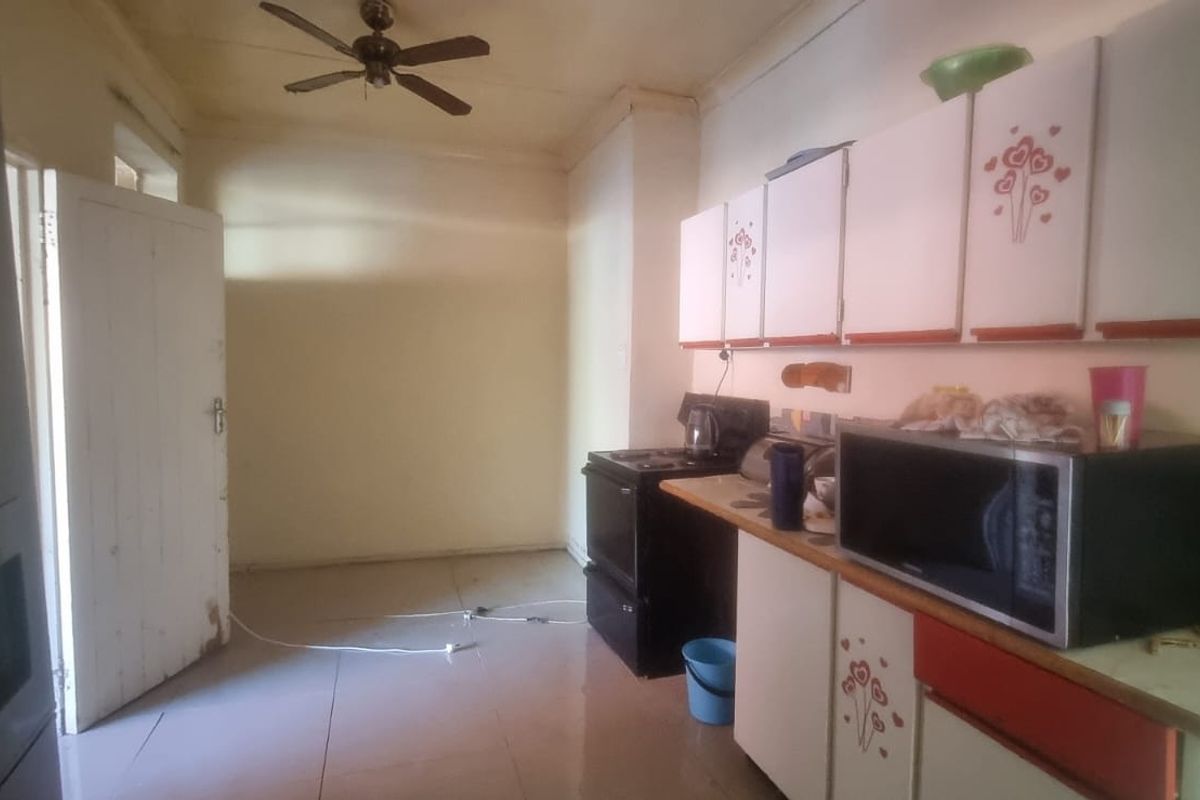 A dated kitchen featuring built-in cabinetry, a freestanding stove, and tiled flooring, offering potential for a modern renovation.