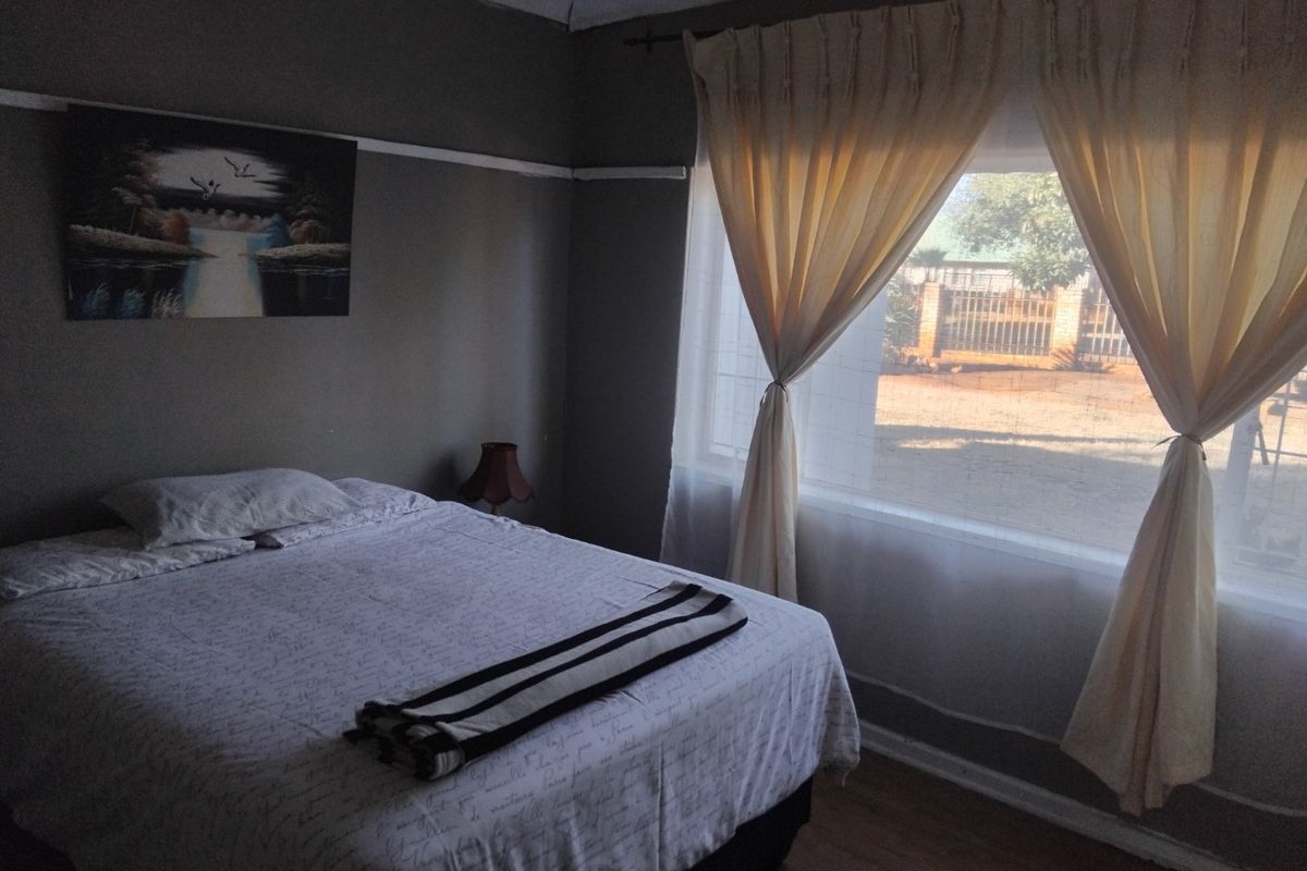 A bedroom featuring laminate flooring and a picture rail, with natural light entering through a large window.