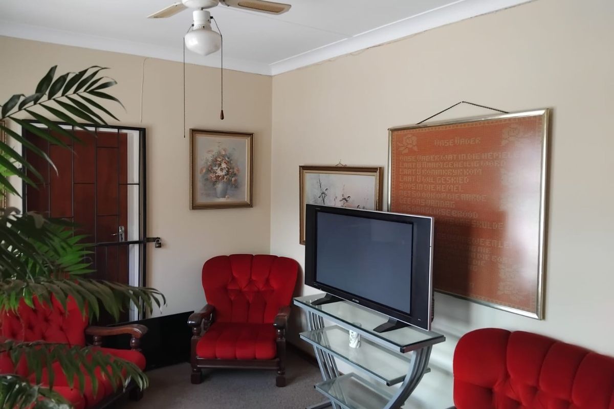 A living room featuring a ceiling fan, security gate, and neutral wall finishes, offering a functional space with potential for modernization.