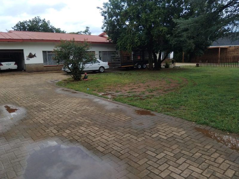 Front exterior view of the house featuring a paved driveway, attached garage, and established garden area.