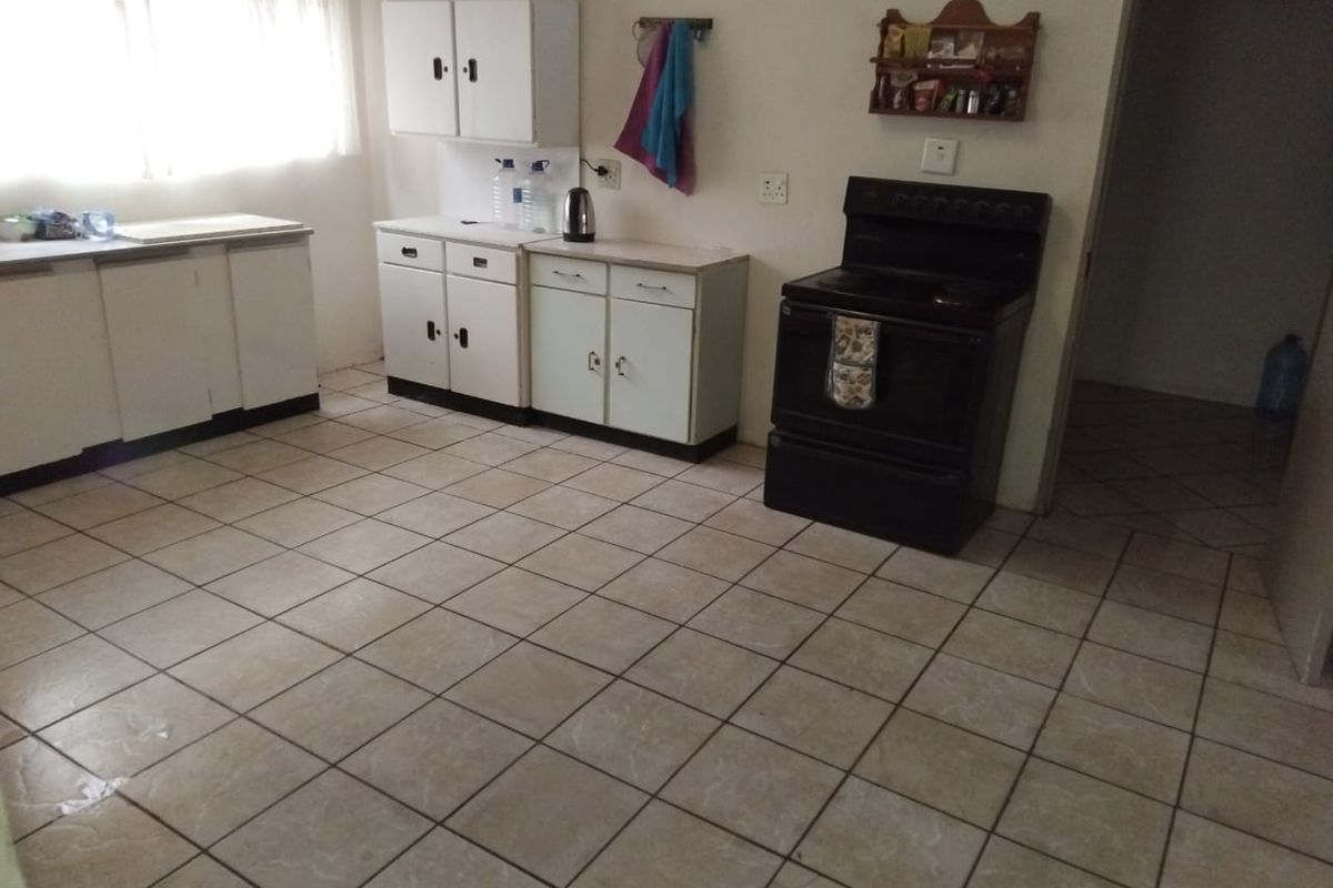 A functional kitchen featuring tiled flooring, built-in cabinetry, and a freestanding stove, offering a practical layout with potential for modern updates.