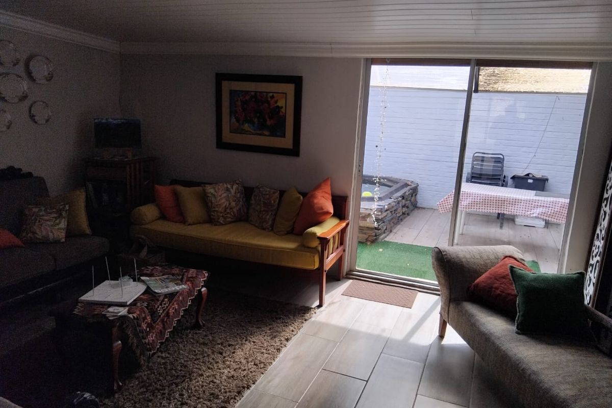 A living room featuring tiled flooring and a sliding glass door providing access to an outdoor patio area.
