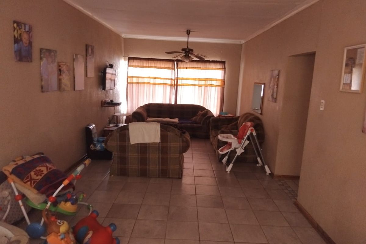 A spacious living room featuring tiled flooring and a ceiling fan, offering a functional layout with natural light from the window.